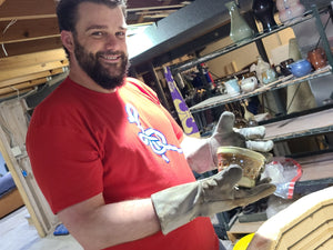 Chris pulling a brand new piece out of the kiln with a great big grin on his face.