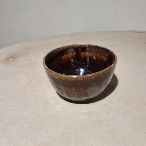 Carved ceramic bowl with deep brown glaze that flows over the facets subtly carved into the surface.