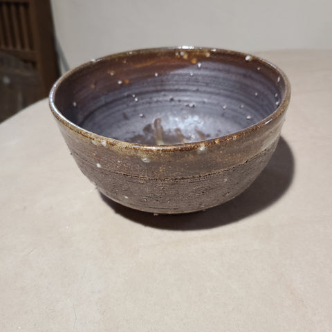 Angled view of carved ceramic bowl that contrasts the glossy toasted marshmallow glazed exterior with the matte, iron-based glaze on the interior.