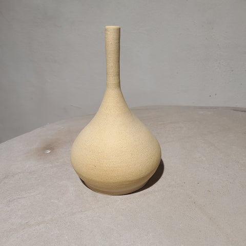 Ceramic bud vase with raw clay surface without glaze creating a rustic, earthy feel. 
